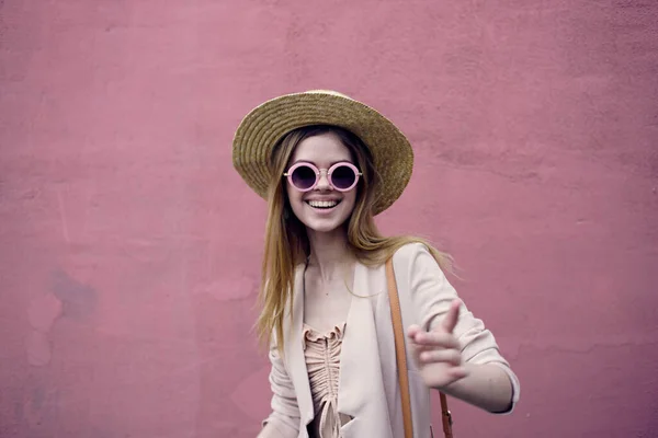 Emotionell kvinna i hatt promenader i staden utomhus mot rosa vägg bakgrund — Stockfoto
