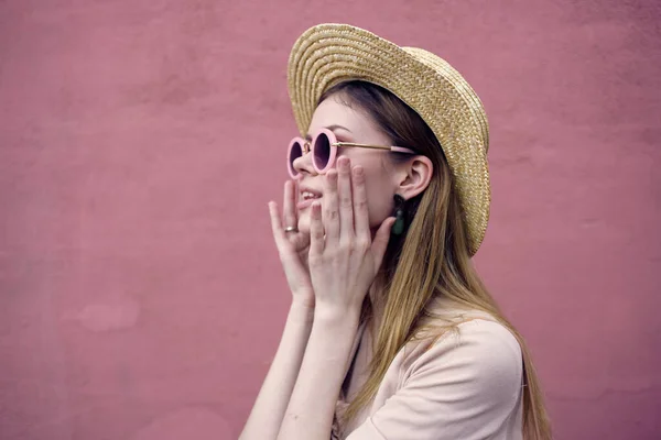 Vacker kvinna i solglasögon mode hatt promenad rosa vägg — Stockfoto