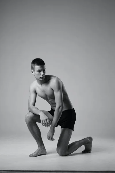 Foto hitam dan putih dari seorang atlet di dalam ruangan dalam pertumbuhan penuh pada satu lutut — Stok Foto