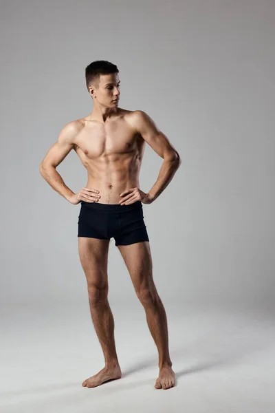 Sexy atleet houdt handen op een riem in volle groei op een grijze achtergrond bodybuilder fitness Copy Space — Stockfoto