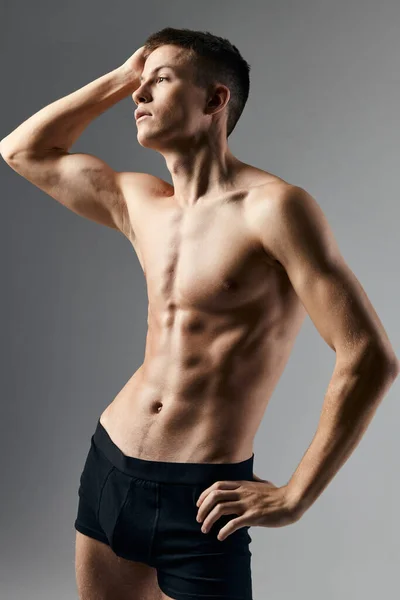 Fisiculturista fitness homem com um bombeado-up torso mão atrás cabeça cinza fundo modelo recortado vista — Fotografia de Stock