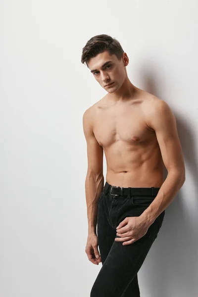 Un tipo con un torso desnudo sobre un fondo claro en pantalones vista recortada —  Fotos de Stock