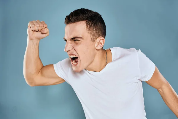 Man gebaart met zijn handen emoties wit t-shirt expressie blauw achtergrond — Stockfoto