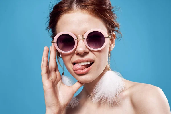 Güzel bir kadın çıplak omuzlu, tüylü küpeli güneş gözlüğü aksesuarlı makyaj malzemesi. — Stok fotoğraf