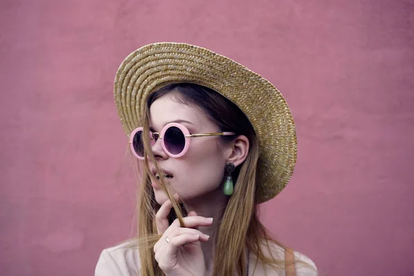 Jolie femme en lunettes de soleil et chapeau sourire regard attrayant fond rose — Photo