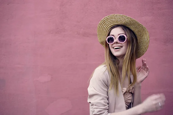 Vacker kvinna i solglasögon gå den rosa väggen utomhus — Stockfoto