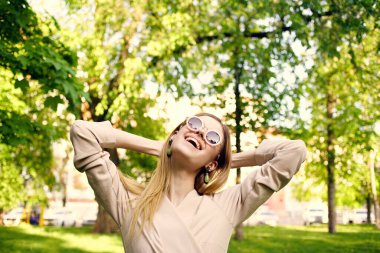 Parkta güneş gözlüklü neşeli bir kadın.