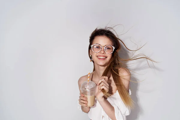 Jolie femme lunettes à la mode décoration sourire verre avec boisson charme fond clair — Photo