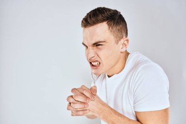 Duygusal adam elleri ile jestler hoşnutsuz beyaz tişört ışıklı arka plan