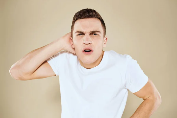 Emotional man facial expression gesture with hands white t-shirt beige background — Stock Photo, Image