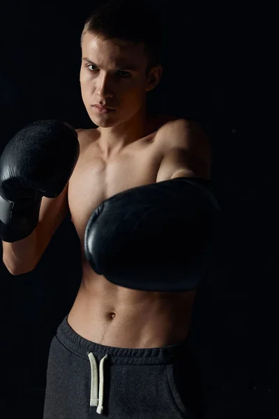Sportovec v černé boxerské rukavice na tmavém pozadí kulturista fitness model — Stock fotografie