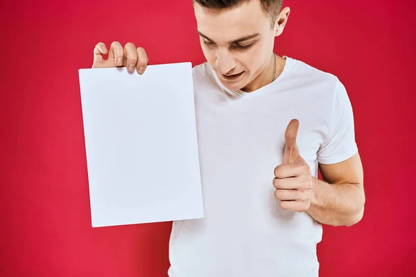 Homme émotionnel tenant une feuille de papier espace de copie t-shirt fond rouge — Photo