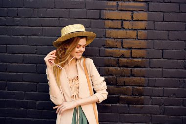 Şapkalı zarif bir kadın, yürüyen temiz tuğlalı siyah bir duvar.