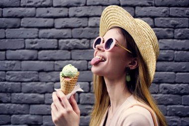 Güneş gözlüklü bir kadın şehrin tuğla duvarında yürüyor.