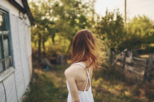 Happy traveler in countryside near buildings outdoors trees back view — Stock Photo, Image