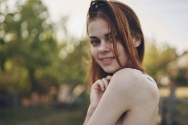 Arka planda yaz tatilinde bahçede ve ağaçlarda kızıl saçlı bir kadının portresi.