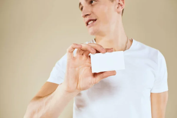 Hombre con una tarjeta de visita en manos de un gerente de oficina de fondo beige Copiar espacio —  Fotos de Stock