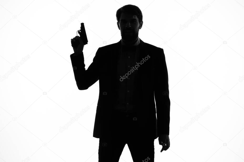 shadow of a man with a gun in his hands aiming detective crime light background