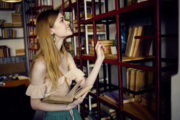 Hübsche Frau in der Bibliothek sucht Buch und liest Urlaub — Stockfoto