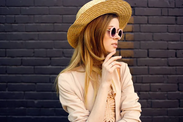 Pretty woman in hat wearing sunglasses outdoors in the city brick wall — Stock Photo, Image