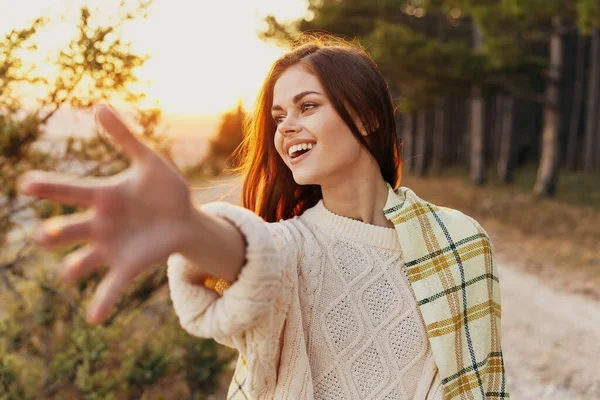 Een vrouw met een warme deken op haar schouder strekt haar hand naar voren en zonsondergang natuur frisse lucht — Stockfoto