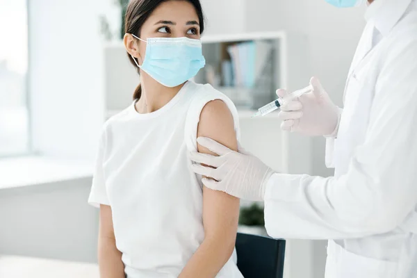 Лікар в захисних рукавичках тримає жіночу руку і вводить вакцину проти коронавірусу — стокове фото