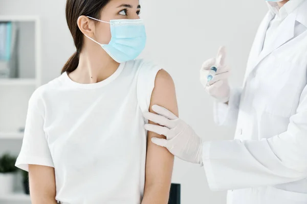 남자 의사가 의료용 마스크를 쓴 여자의 어깨에 예방 접종 주사를 놓는 모습 — 스톡 사진