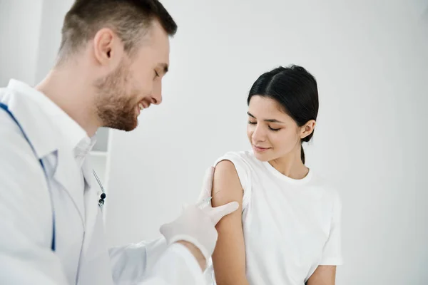 Läkare med stetoskop ger en injektion i skuldran på en kvinna patient som vaccinerats med covid — Stockfoto