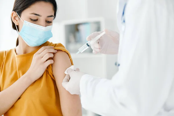 Ασθενής με ιατρική μάσκα κοιτάζει το γιατρό με μια σύριγγα στο χέρι εμβολιασμό — Φωτογραφία Αρχείου