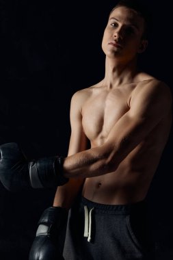 Siyah arkaplan portresi üzerinde boks eldivenleri giyen bir sporcu.