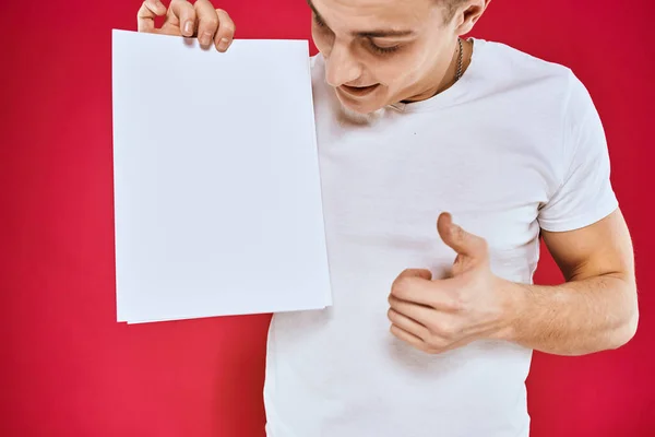 Emotionele man met een vel papier kopieerruimte t-shirt rode achtergrond — Stockfoto