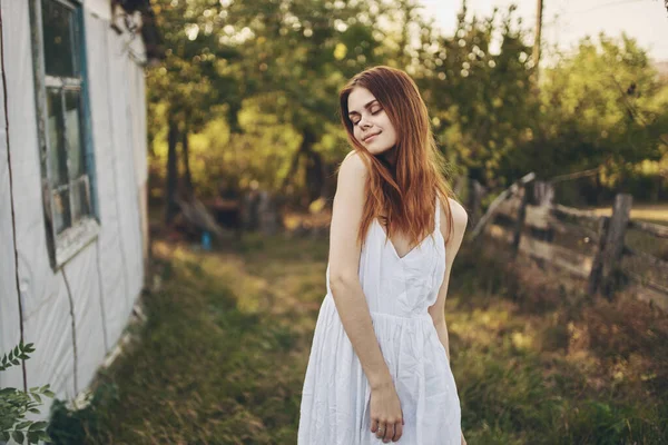 Mulher feliz em um vestido de verão branco perto do edifício na natureza e árvores no fundo — Fotografia de Stock