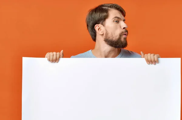 Bärtiger Mann mit Plakat in der Hand auf orangefarbenem Hintergrund — Stockfoto