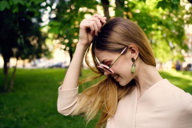 Güneş gözlüğü takan güzel bir kadın yeşil çimen manzaralı temiz hava.