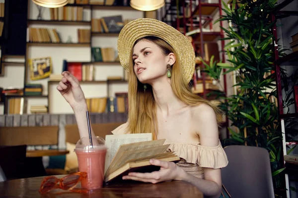 Hübsche Frau mit Hut und Buch in der Hand liest Urlaub im Café — Stockfoto