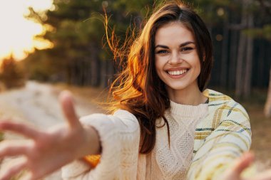 Mutlu kadın kollarını ileri uzatıyor ve sıcak süveter doğa kozalakları.