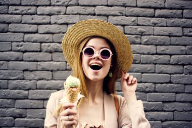 Dondurmalı şapkalı bir kadın, tuğla duvarın arkasında.