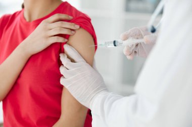 Bir doktor, bir kadının omzuna aşı enjekte eder.