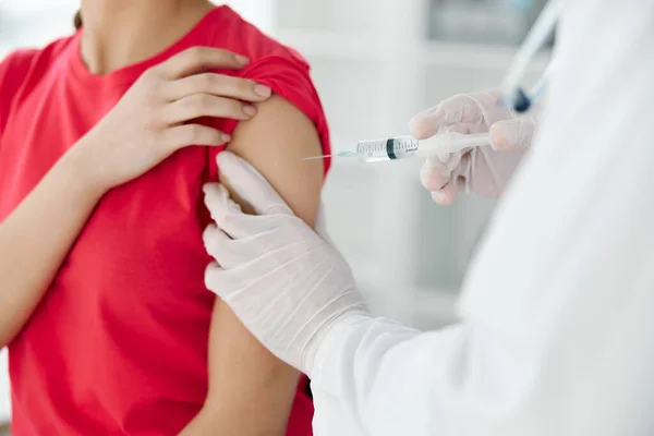 a doctor injects a vaccine into the shoulder of a woman patient close-up