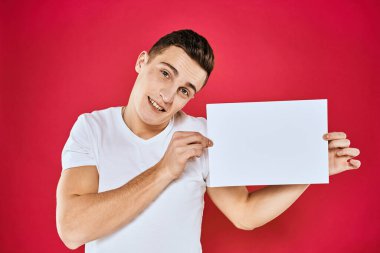 Elinde beyaz sayfa fotokopi odası kırmızı arka planı olan bir adam.