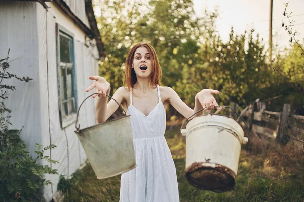 Hur var det en lycklig kvinna med hinkar nära en byggnad i en naturgård by — Stockfoto