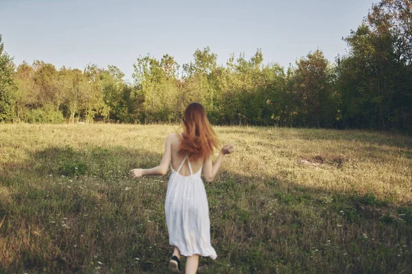 Feliz viagem em um vestido de verão branco correndo na grama na natureza — Fotografia de Stock