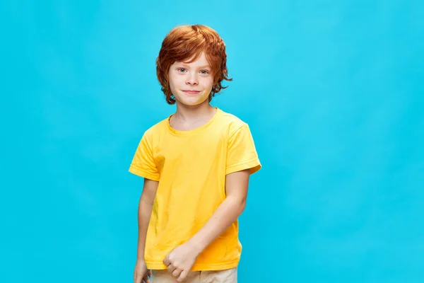 赤毛の子供の笑顔黄色のTシャツスタジオ青の背景 — ストック写真