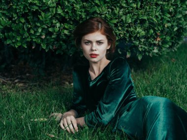 Güzel bir kadın çimenlerin üzerinde uzanır yeşil çalı doğası taze hava cazibesi zarif bir tarz.