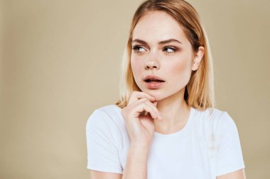Güzel kadın beyaz tişörtlü eğlenceli duygular bej arka plan kırpılmış görünüm