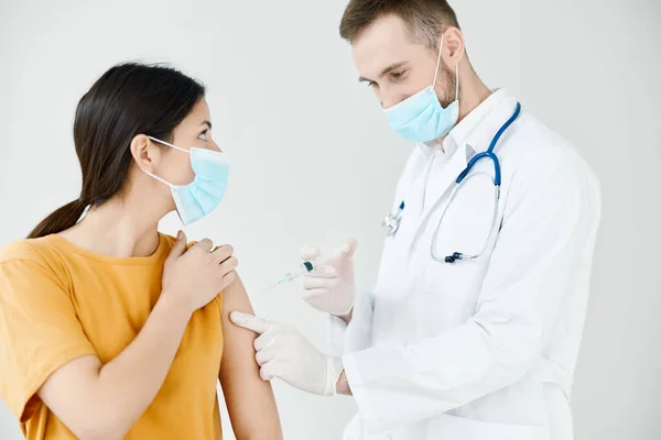 Un paziente con una maschera medica guarda un medico con una siringa nella sua infezione della vaccinazione della mano — Foto Stock