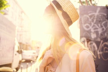 Zarif bir kadın, güneşli bir günde şehir tarzı yürür.