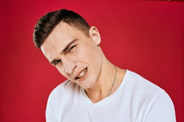 Beyaz tişörtlü adam, yüz ifadesinden memnun değil.