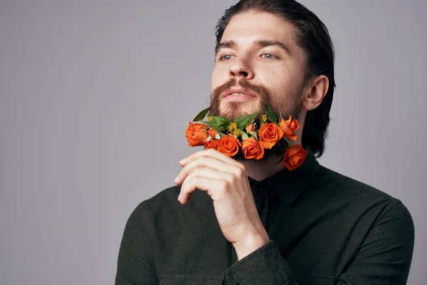 Elegant man with flowers in a beard,  decoration, studio background. High quality photo