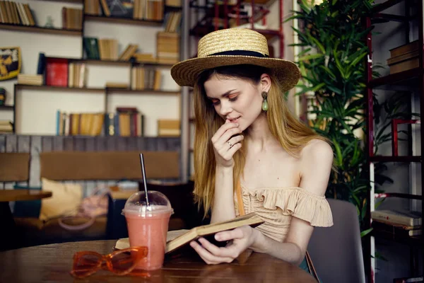 Kvinna med hatt sitter i café zastava glas med dryck vila bok — Stockfoto